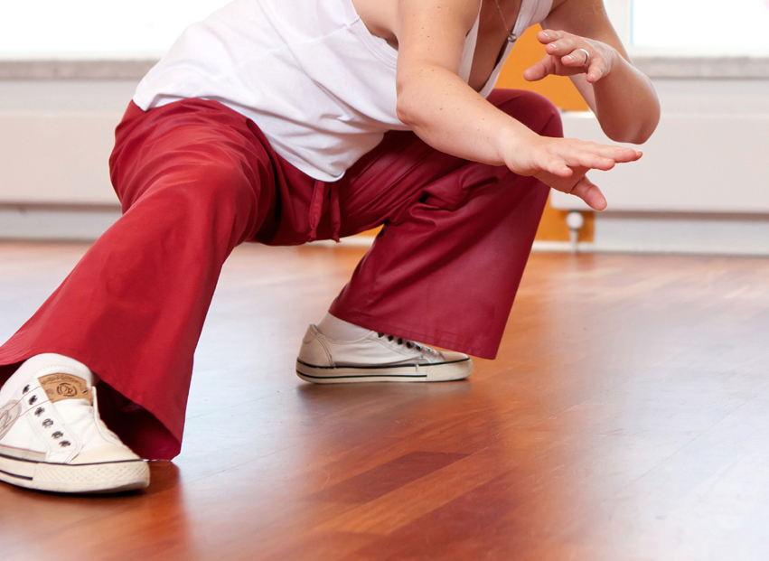 Frau in roter Hose und weiem Top bei anstrengender Tai Chi-bung